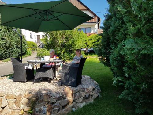 a man sitting at a table under an umbrella at Vakantieappartement Achat Duitsland in Wirschweiler