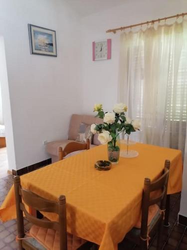 a dining room table with a vase of flowers on it at Apartments Vedrana in Ražanj