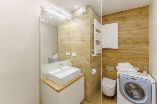 a bathroom with a sink and a washing machine at SUN 7 - osiedle JANTAR in Kołobrzeg