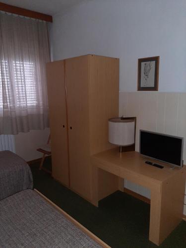 a bedroom with a desk with a television and a cabinet at Hotel Cucciolo in Donoratico