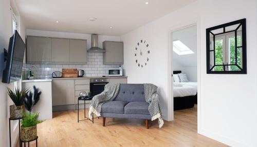a living room with a blue chair and a kitchen at The Kop End Penthouse in Liverpool