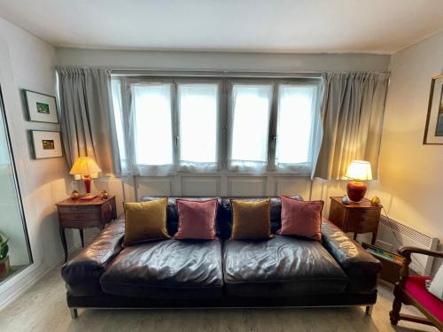 a living room with a leather couch in front of a window at Grand T2 Plein centre historique avec ascenseur in Saint-Jean-de-Luz