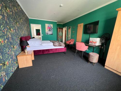 1 dormitorio con cama, paredes verdes y escritorio en SmartHotel Flamingo Self check-in, en Giessen