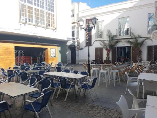 patio ze stołami, krzesłami, stołami i budynkami w obiekcie Apartamentos San Hiscio w mieście Tarifa
