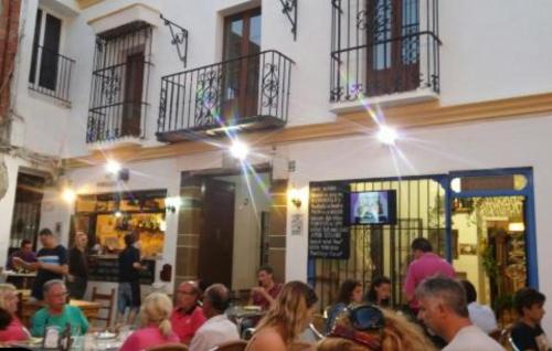 grupa ludzi siedzących przy stolikach przed restauracją w obiekcie Apartamentos San Hiscio w mieście Tarifa