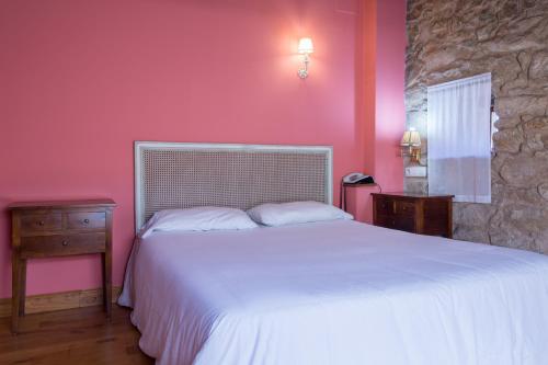 1 dormitorio con cama blanca y pared rosa en Asador de Roxos Casa Albardonedo, en Santiago de Compostela