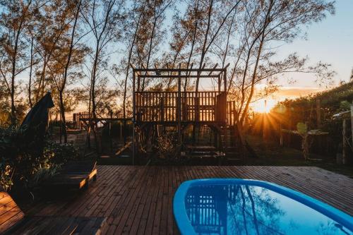 a backyard with a pool and a gate and the sunset at Pousada Estação Sol e Lua in Florianópolis