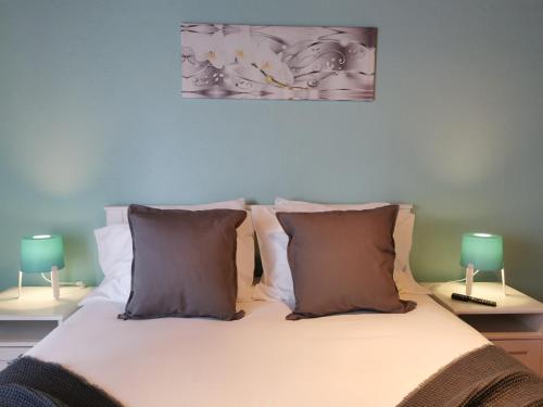 um quarto com uma cama com almofadas e 2 candeeiros em Casa da Eira Velha em Fajã do Ouvidor