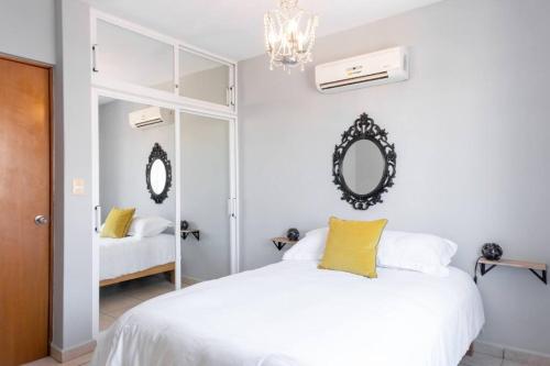 a white bedroom with a bed and a mirror at Surf House! Bonita casa vacacional en excelente ubicación in Mazatlán