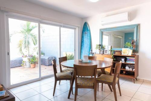 a dining room with a table and chairs and a large window at Surf House! Bonita casa vacacional en excelente ubicación in Mazatlán