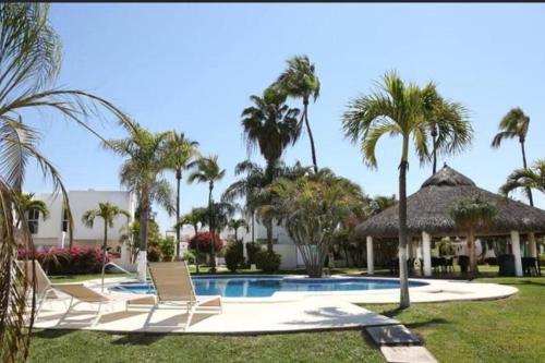 a pool with lounge chairs and palm trees at Surf House! Bonita casa vacacional en excelente ubicación in Mazatlán