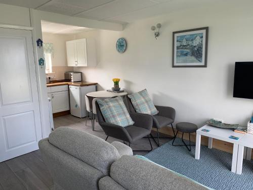 a living room with a couch and chairs and a kitchen at Chalet 26 Widemouth Bay in Bude