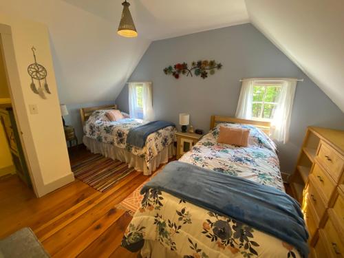 a attic room with two beds and a window at Romantic, Secluded Historic Cottage on 5 Acres 30 mins to TIEC in Landrum