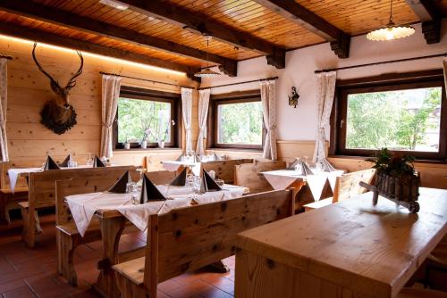 a restaurant with wooden tables in a room with windows at Baita da Rico Zoncolan in Sùtrio