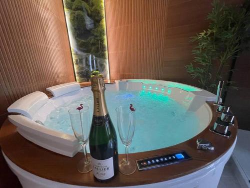 een hot tub met een fles champagne en 2 wijnglazen bij Esprit BALI ....LOVE SPA, Sauna de luxe à Mulhouse in Mulhouse