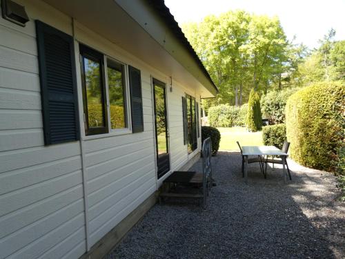 una mesa junto a un edificio con un banco al lado en Chalet nr 10 op Bospark Trimunt, en Marum