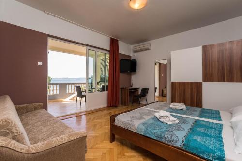 ein Schlafzimmer mit einem Bett und einem Sofa sowie einem Balkon in der Unterkunft Guest House Malenica in Sukošan