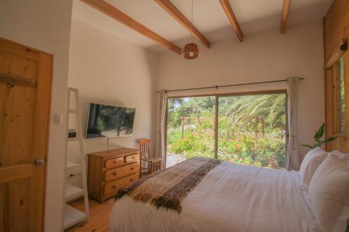 1 dormitorio con 1 cama y puerta corredera de cristal en Cabañas en la naturaleza a pasos de la Playa en La Serena