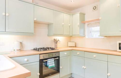 a kitchen with white cabinets and a stove top oven at Stunning 2 bed Cottage in Saddleworth in Dobcross