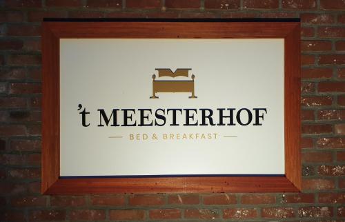 a framed picture of a bed and breakfast sign on a brick wall at B&B 't Meesterhof in Deinze
