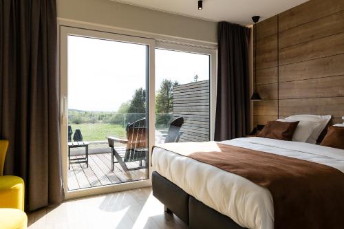 a bedroom with a large bed and a sliding glass door at Le Mont Rigi in Waimes