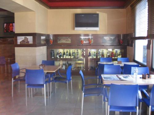a restaurant with blue chairs and tables and a bar at Hotel Machaco in Alburquerque