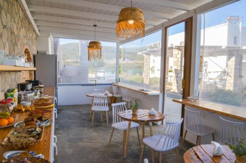 a restaurant with tables and chairs in a room with windows at Hawk Stone in Adamas