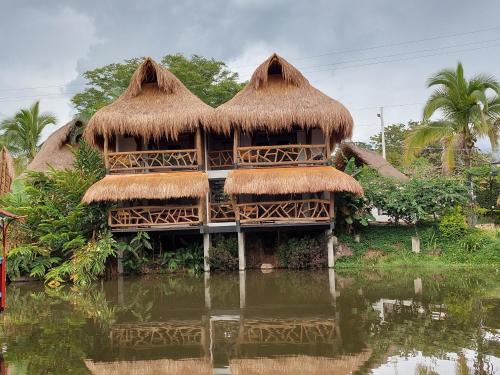 atropical house with thatched roofs in the water at Hotel Campestre San Joaquin in Garzón