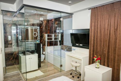 uma casa de banho com uma cabina de duche em vidro e uma banheira em Hotel Pazari & Apartments em Korçë