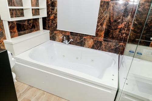 a bathroom with a white tub and a mirror at Hotel Pazari & Apartments in Korçë