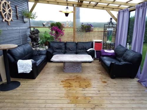 a living room with black leather couches and a table at Garden Guest House Room with Terrace in Stavanger