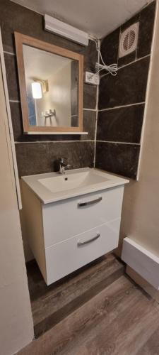 une salle de bain avec un lavabo blanc et un miroir dans l'établissement Maison de village en Provence avec terrasse de 33m2, à Saint-Roman-de-Malegarde