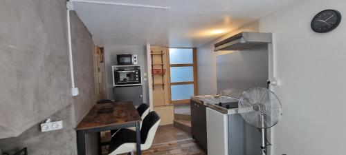 Il comprend une petite cuisine avec une table et un ventilateur. dans l'établissement Maison de village en Provence avec terrasse de 33m2, à Saint-Roman-de-Malegarde