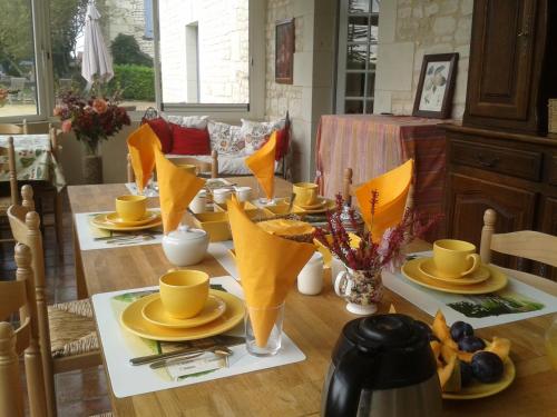 une table à manger avec des serviettes jaunes et des tasses jaunes dans l'établissement Château de Bournand B&B, à Bournand