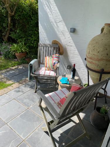 a patio with a chair and a table with a bottle of wine at Cliff top Garden room in Milford on Sea