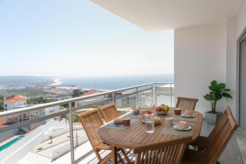 a dining table on a balcony with a view of the ocean at Casa Urlaub in Nazaré