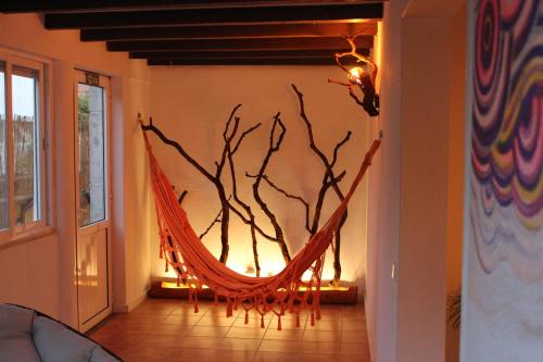 a hammock in a room with a tree on the wall at 5th Element Beach House Caparica in Costa da Caparica