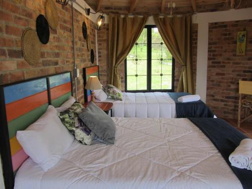 een slaapkamer met 2 bedden en een bakstenen muur bij Posada Rural, Colinas y Senderos in Paipa