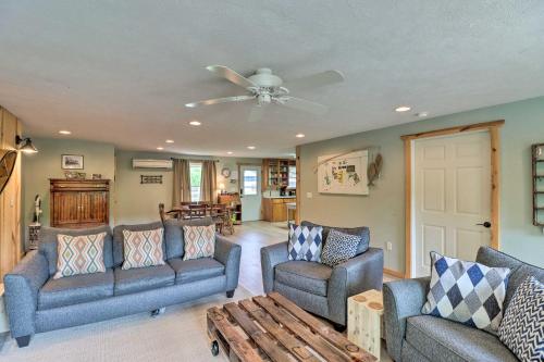 a living room with two couches and a ceiling fan at Expansive Cotter Cabin on White River with Deck! in Cotter