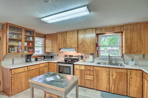 a kitchen with wooden cabinets and a sink and a table at Expansive Cotter Cabin on White River with Deck! in Cotter