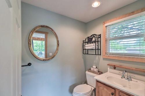 a bathroom with a mirror and a toilet and a sink at Expansive Cotter Cabin on White River with Deck! in Cotter