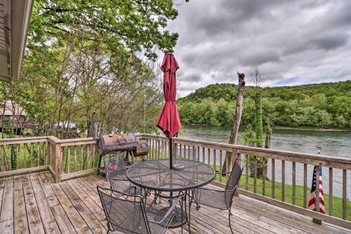 a table with chairs and an umbrella on a deck at Expansive Cotter Cabin on White River with Deck! in Cotter