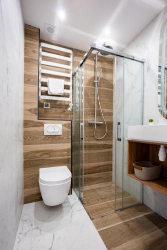 a bathroom with a shower and a toilet and a sink at Rajskie Uroczysko Apartamenty Jacuzzi Sauna in Rajskie Sakowczyk