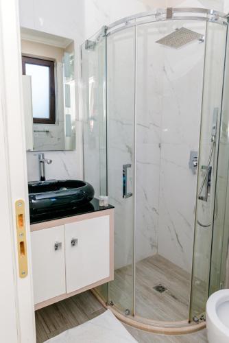 a bathroom with a glass shower with a sink at Hotel Pazari & Apartments in Korçë