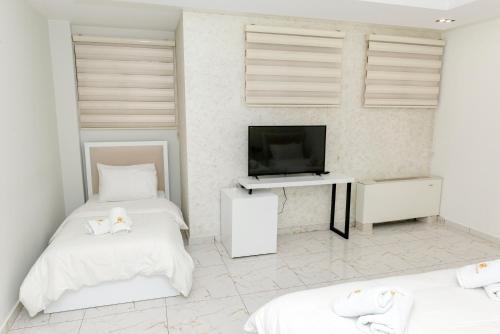 a white room with two beds and a television at Hotel Pazari & Apartments in Korçë