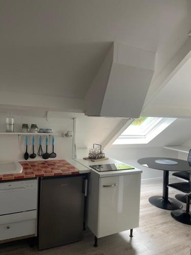 a kitchen with white cabinets and a table in a room at Les Gîtes de La Maison Bleue d'Estialescq in Estialescq