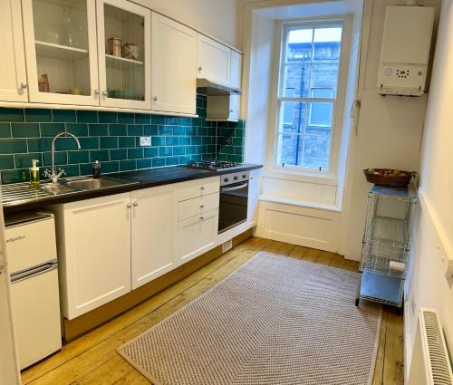 eine Küche mit weißen Schränken und einer Spüle und einem Fenster in der Unterkunft Old Town Centre Apartment 5 mins to Edinburgh Castle in Edinburgh