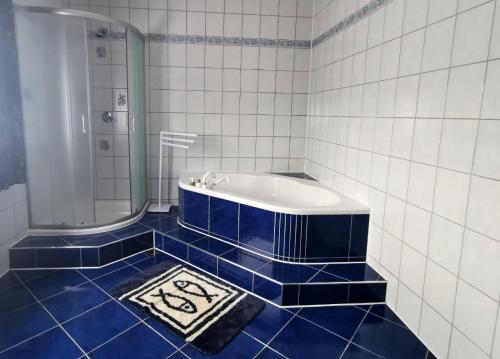 a blue and white bathroom with a tub and a rug at Ella in Velika