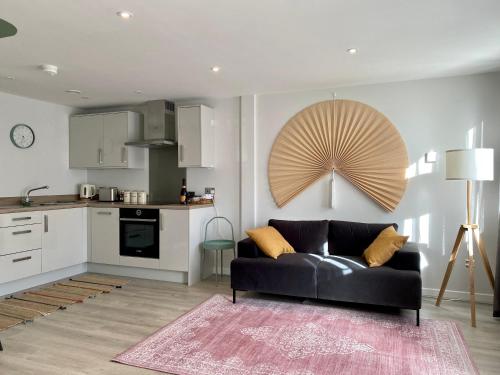 a living room with a black couch and a kitchen at Modern apartment in central quiet York with free Parking - Contemporary new building in York