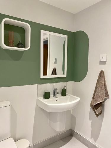 a bathroom with a sink and a mirror and a toilet at Modern apartment in central quiet York with free Parking - Contemporary new building in York